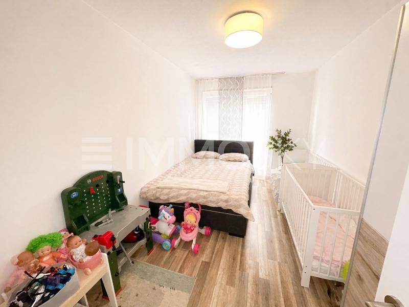 Gemütliches Schlafzimmer mit Doppelbett, Babybett und Spielzeug, ideal für eine junge Familie.