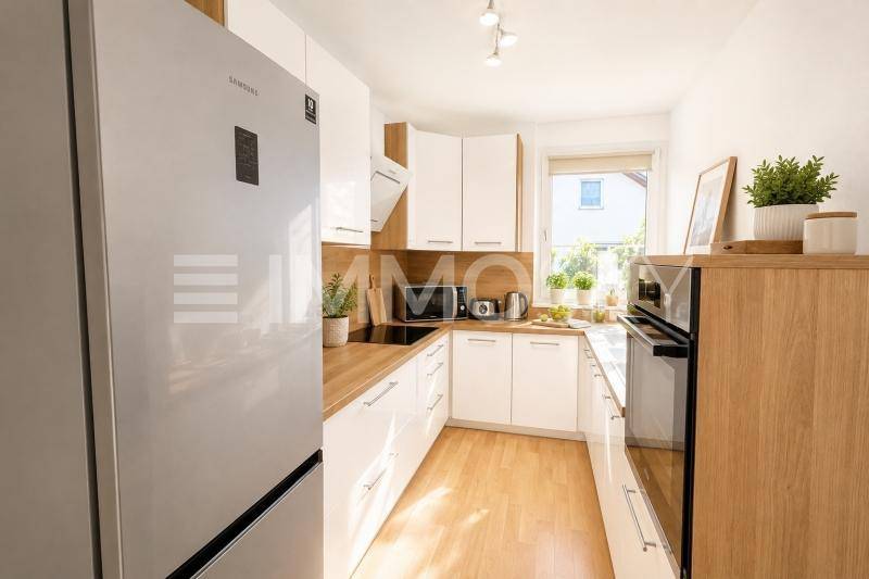 Moderne Küche mit weißen Schränken, Holzarbeitsplatten und Fenster.