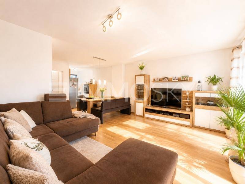 Heller offener Wohn- und Essbereich mit bequemer Couch und Holzboden.
