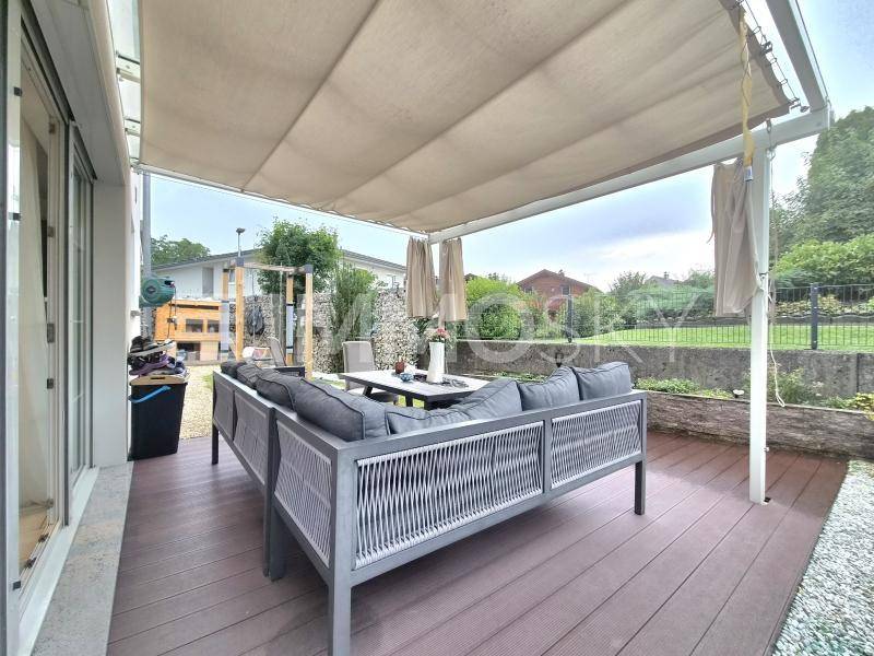Gemütliche Terrasse mit modernen Gartenmöbeln und ausfahrbarer Markise, umgeben von Grün.