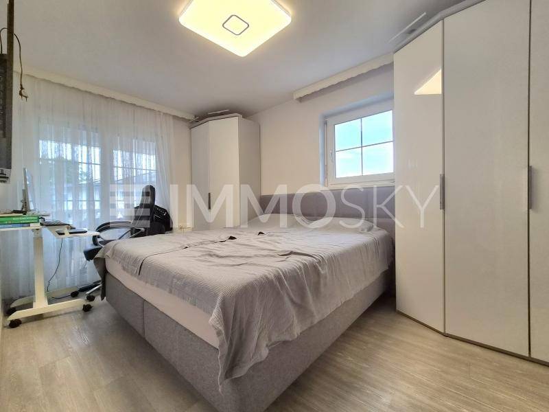 Helles Schlafzimmer mit Doppelbett, weißen Einbauschränken und Fenster für natürliches Licht.