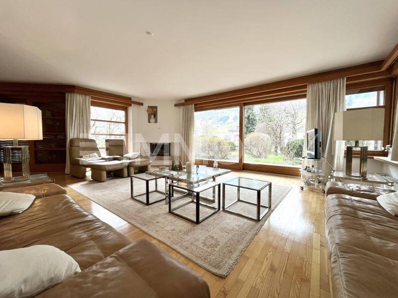 Helles Wohnzimmer mit großen Fensterfronten, die viel Tageslicht hereinlassen und Gartenblick bieten.