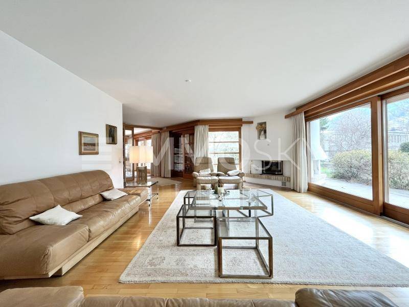 Geräumiges Wohnzimmer mit bequemen Ledersofas, Holzboden und großen Fenstern zum Garten.