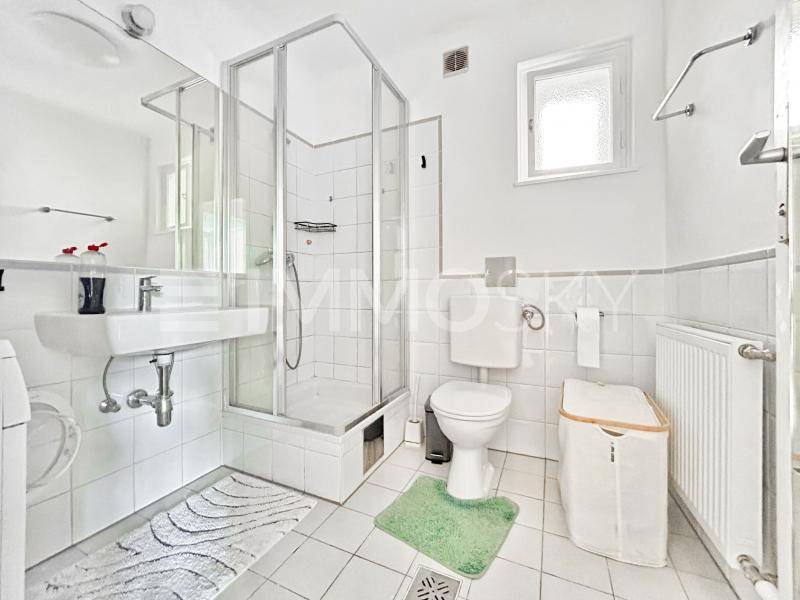 Funktionales Badezimmer mit Duschkabine, Waschbecken, WC und einem Fenster für Tageslicht.
