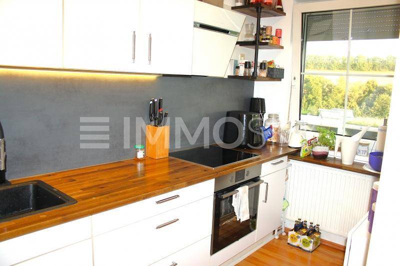 Moderne Küche mit weißen Schränken, Holz-Arbeitsplatte und Induktionskochfeld.