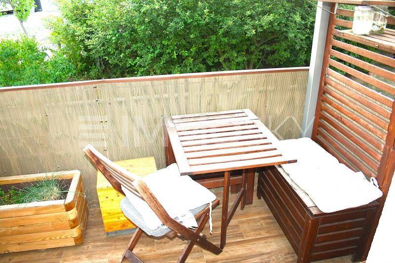 Gemütlicher Balkon mit Holzboden, Sitzgelegenheiten und Blick ins Grüne.