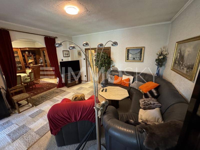 Gemütliches Wohnzimmer mit großer Ledercouch, Teppichboden und traditioneller Einrichtung.