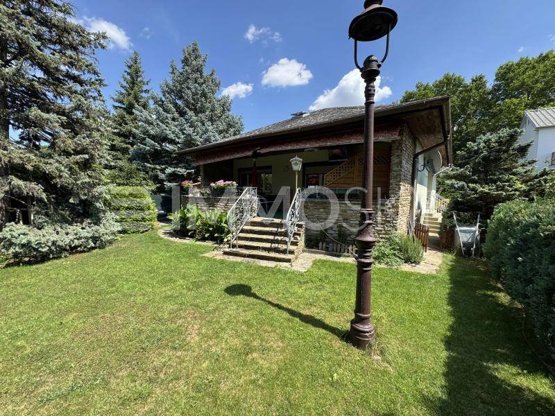 Gepflegter Gartenbereich mit Rasen und altem Baumbestand vor einem traditionellen Haus.