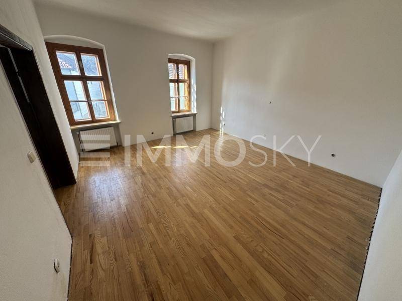Helles Wohnzimmer mit schönen Holzböden, hohen Fenstern und weiß gestrichenen Wänden.