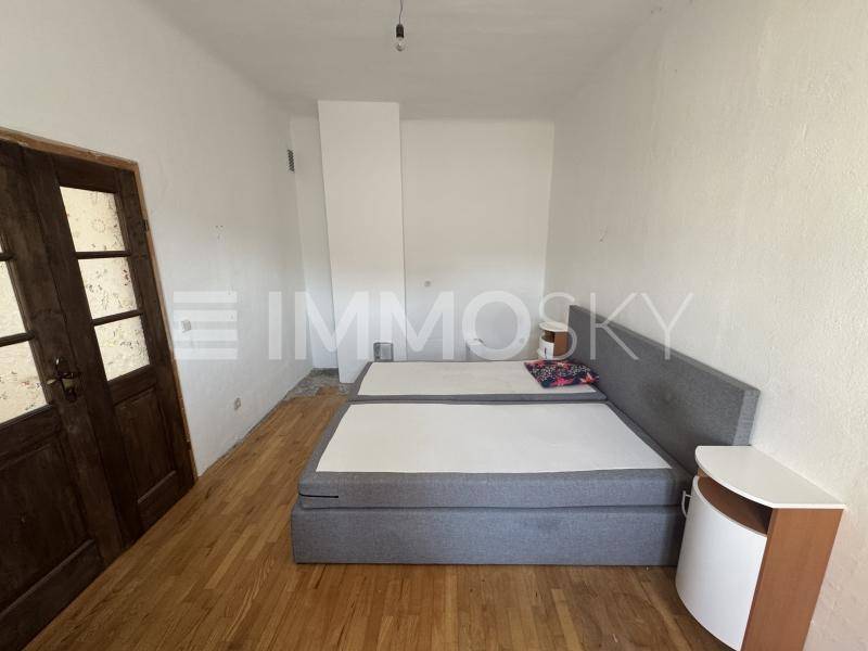 Schlafzimmer mit Holzboden, einem Doppelbett und einer Holztür.