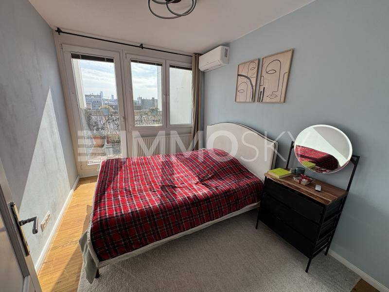 Schlafzimmer mit Balkonzugang, Holzboden, Klimaanlage und Blick auf die Stadt.