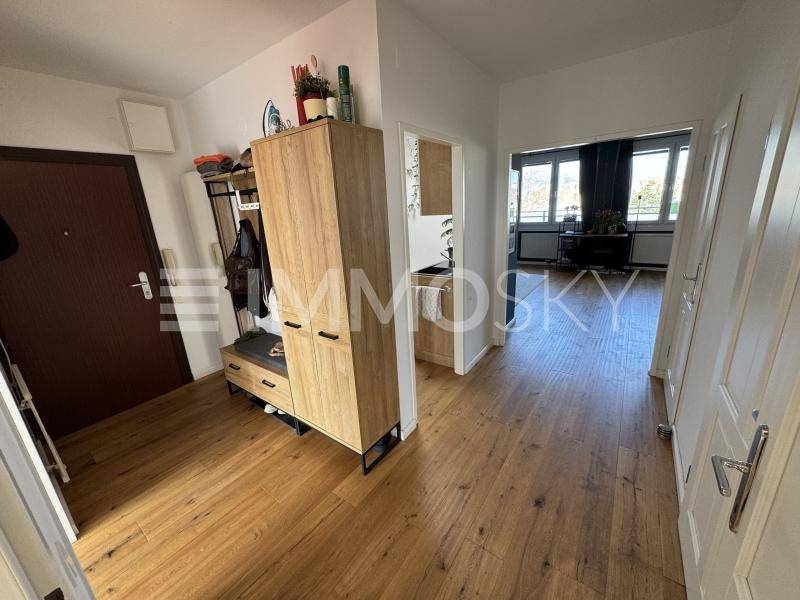 Heller Flur mit Holzboden und Garderobenschrank, der zu weiteren Räumen führt.