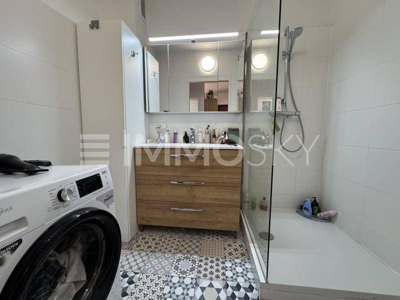 Modernes Badezimmer mit begehbarer Dusche, Waschbecken und Waschmaschine.