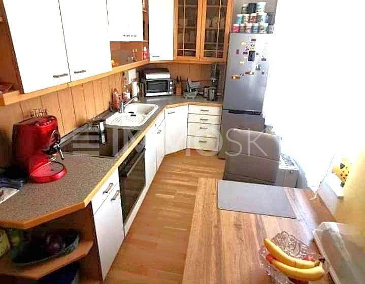 Helle Küche mit Holzelementen, Essbereich und modernen Geräten.