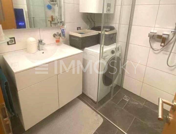 Modernes Badezimmer mit Duschkabine, Waschbecken und Waschmaschine.