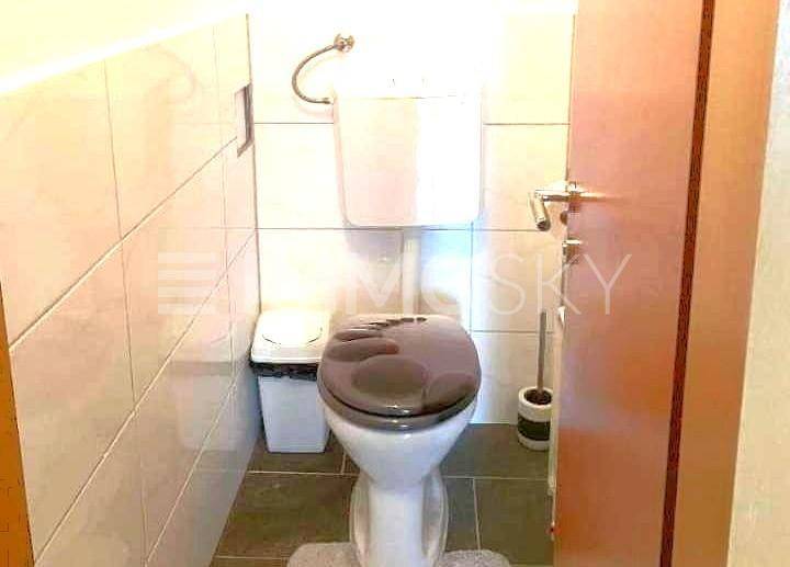 Separates WC mit Toilette und hellen Wandfliesen.