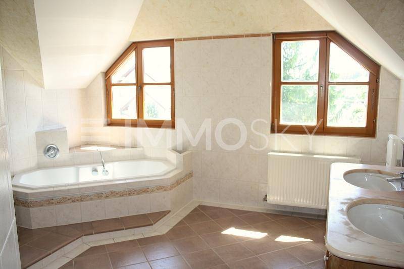 Helles Badezimmer mit Eckbadewanne, Doppelwaschbecken und Dachschrägenfenstern.
