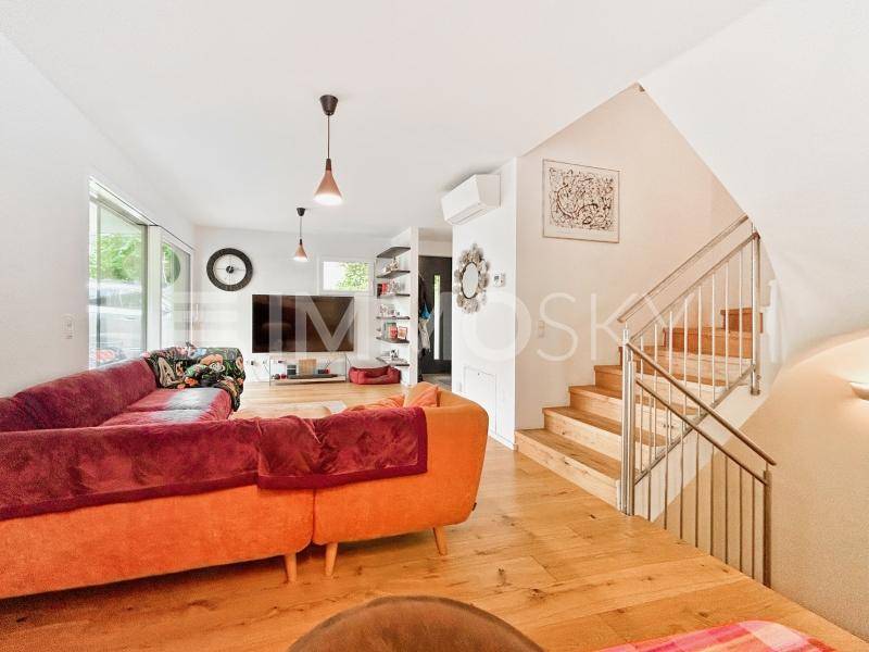Geräumiges Wohnzimmer mit Holztreppe und moderner Einrichtung, ideal für Familienleben.