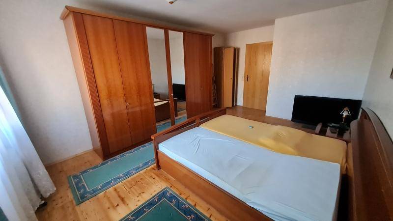 Schlafzimmer mit Holzbett, großem Spiegelschrank und Dielenboden in einem traditionellen Stil.