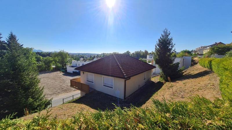Weitläufige Ansicht eines Einfamilienhauses mit großem Grundstück und viel Grün unter blauem Himmel.