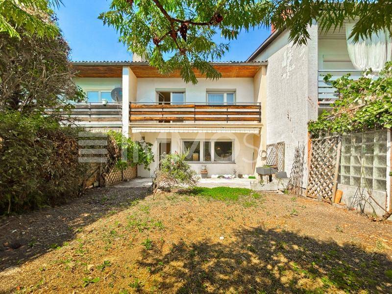 Hinterhof mit Gartenfläche und Blick auf die Rückseite des Hauses mit Balkonen und Terrasse.