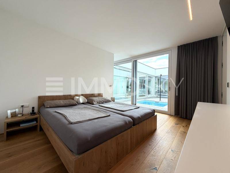 Helles Schlafzimmer mit Holzbett und direktem Zugang zum Außenbereich mit Pool.