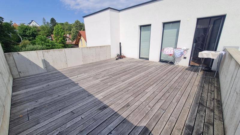 Große Dachterrasse mit Holzboden und Blick auf die Umgebung.