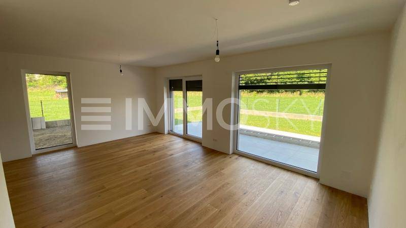 Geräumiges Wohnzimmer mit Holzboden, großen Schiebetüren und Blick ins Grüne.