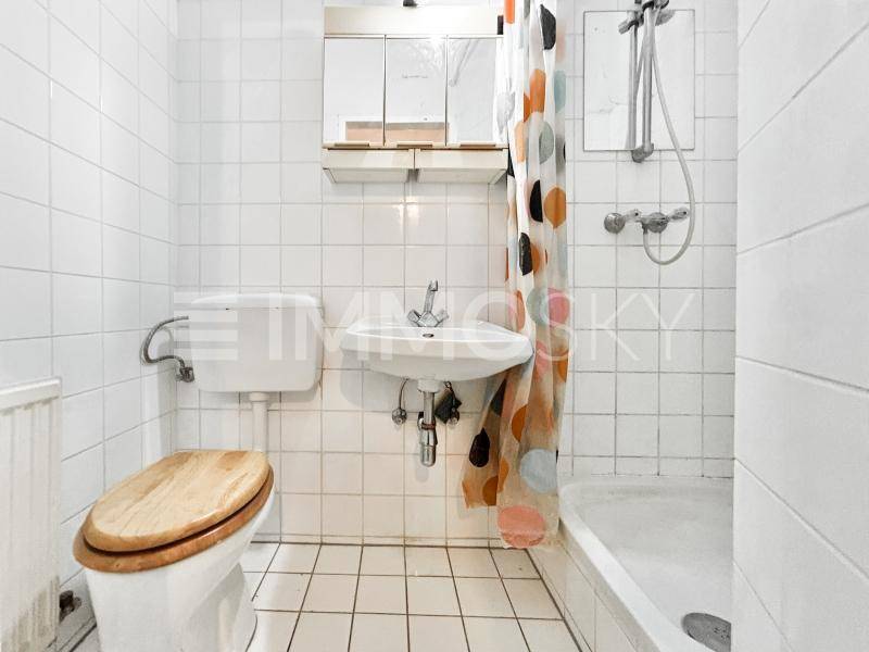 Funktionales Badezimmer mit WC, Waschbecken und Dusch-Badewannen-Kombination, komplett gefliest.