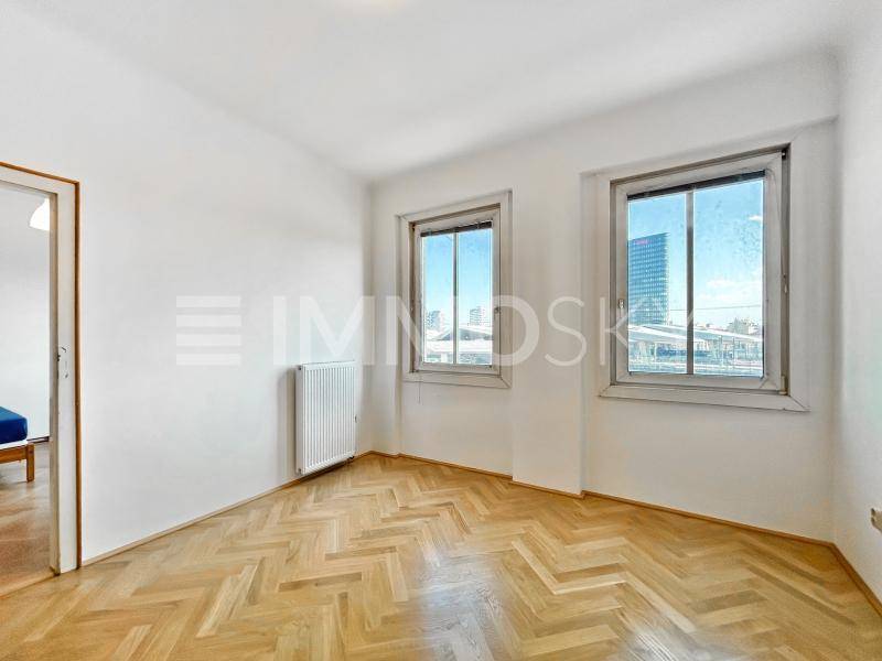 Leeres Zimmer mit Fischgrätparkett, weiß gestrichenen Wänden und Stadtblick.