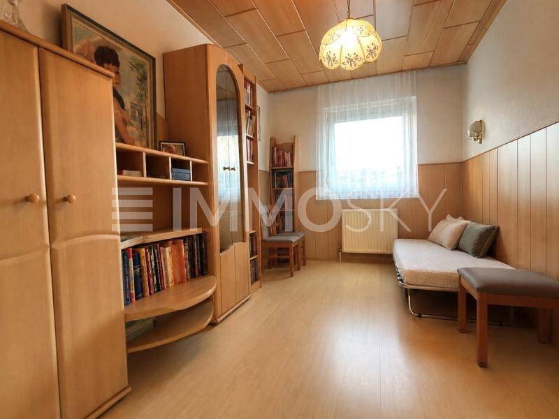 Helles Schlafzimmer mit Holzmöbeln, Laminatboden und einer Holzdeckenverkleidung.
