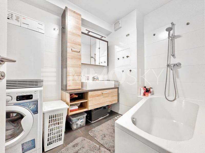 Modernes Badezimmer mit Badewanne, Dusche, Waschmaschine und Trockner.