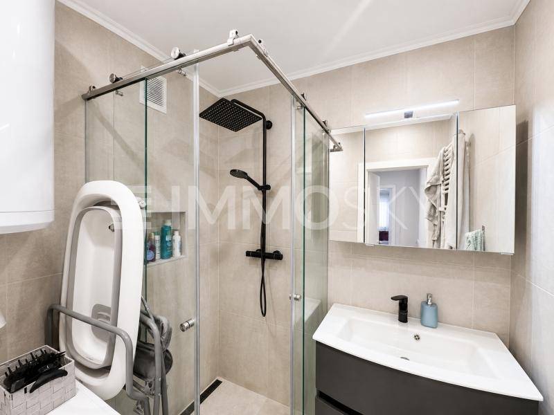 Modernes Badezimmer mit begehbarer Dusche, Einzelwaschbecken und Spiegelschrank.