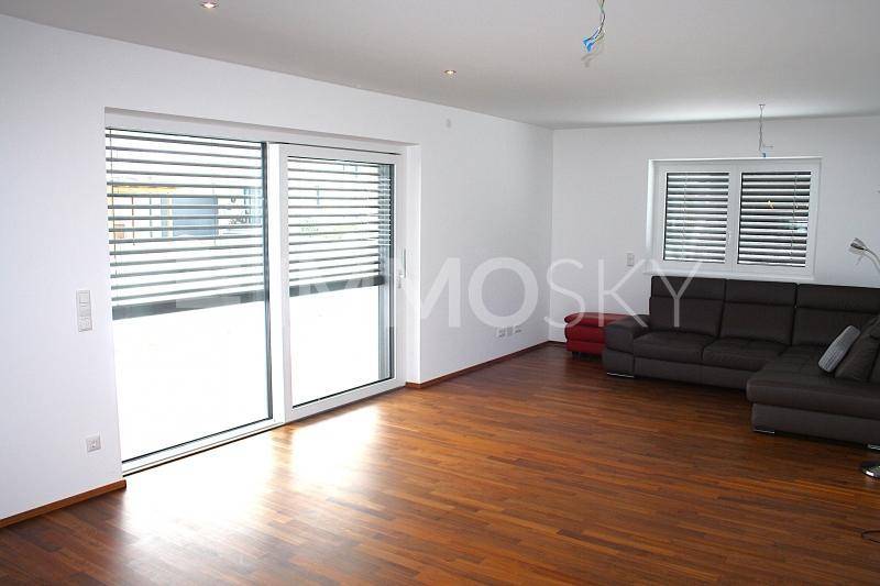 Helles Wohnzimmer mit dunklem Parkettboden, großen Schiebetüren und einer modernen Couch.