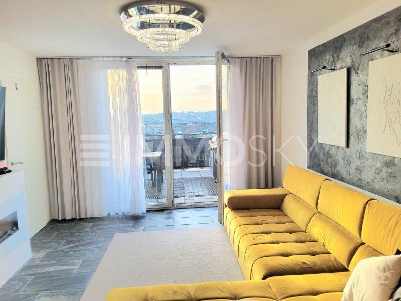 Helles Wohnzimmer mit großem gelben Sofa, modernem Kronleuchter und Zugang zur Terrasse.
