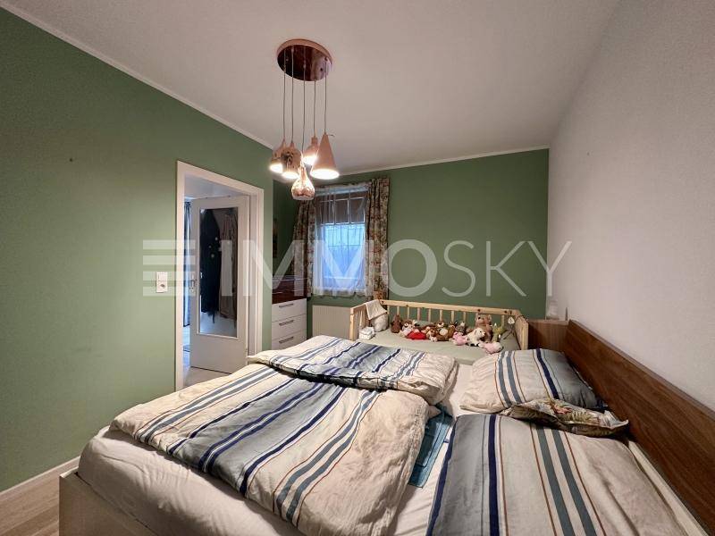 Gemütliches Schlafzimmer mit grünen Wänden, Holzbett und Blick ins Grüne.