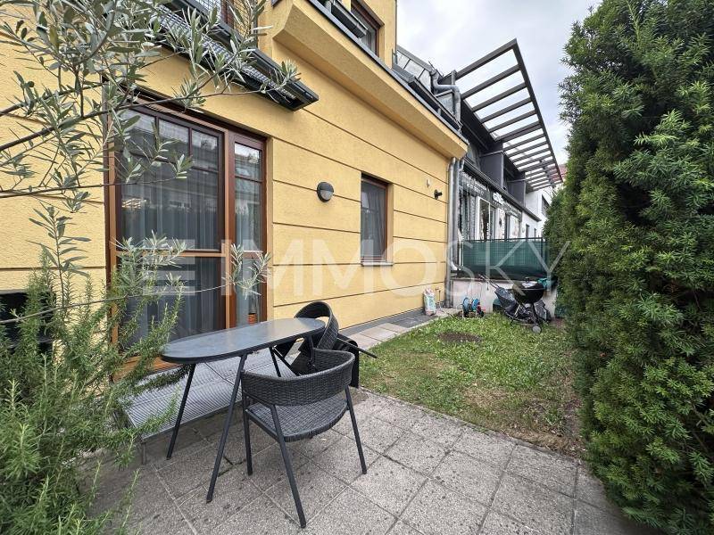 Kleiner Gartenbereich mit Terrasse, Sitzgelegenheiten und grüner Bepflanzung am Haus.
