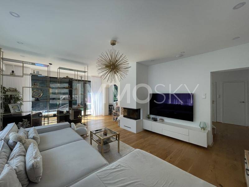 Helles Wohnzimmer mit großem Sofa, modernem TV-Möbel, Holzboden und dekorativer Beleuchtung.
