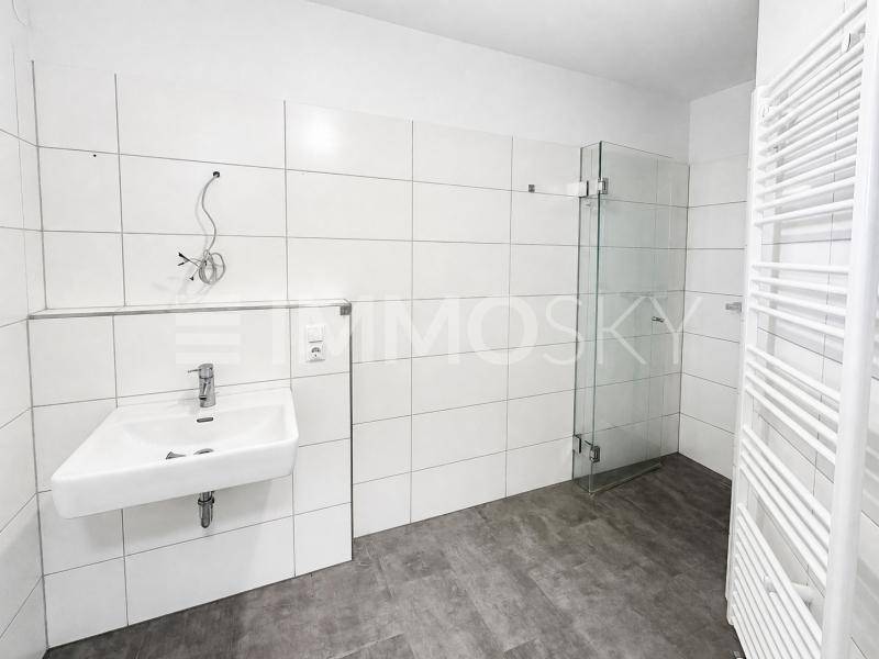 Modernes Badezimmer mit weißen Fliesen, ebenerdiger Dusche und Handtuchheizkörper.