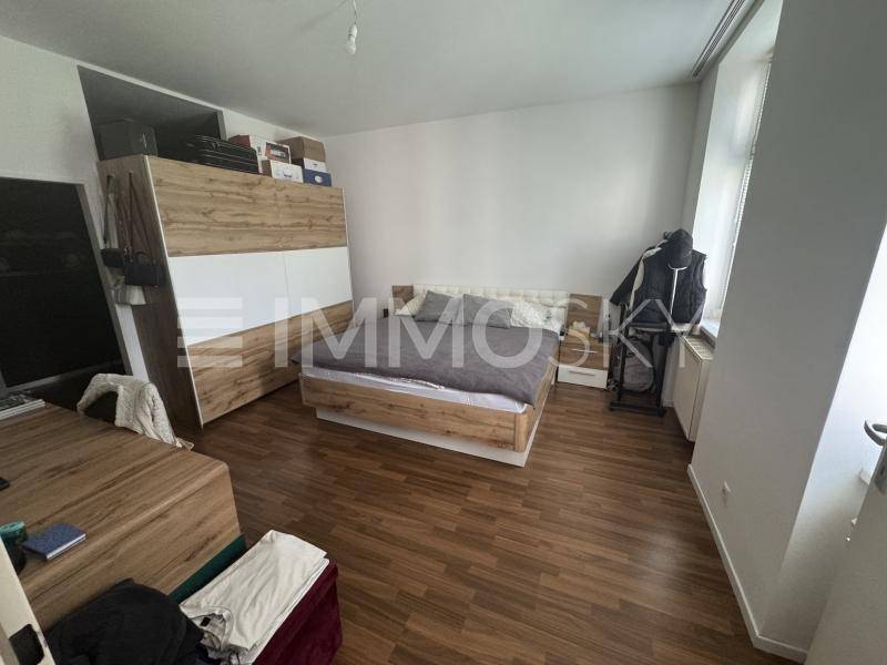 Geräumiges Schlafzimmer mit Holzboden, modernem Bett und großem Kleiderschrank.