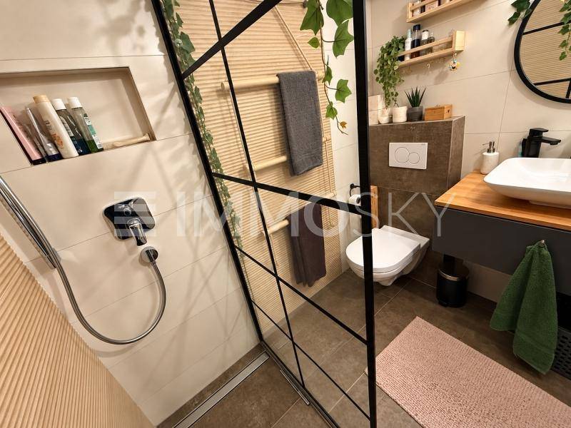 Helles Badezimmer mit moderner begehbarer Dusche, Glasabtrennung und stilvoller Einrichtung.