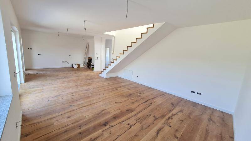 Geräumiger Innenraum mit Holzboden und offener Treppe, ideal für individuelle Gestaltung.
