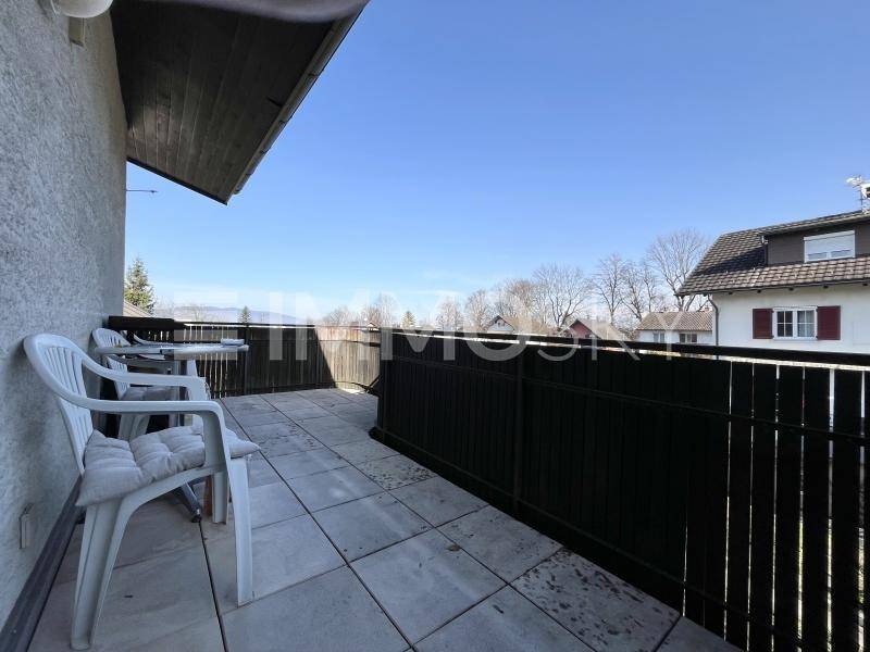 Heller Balkon mit Sitzgelegenheiten, Fliesenboden und weitem Blick über die Nachbarschaft.