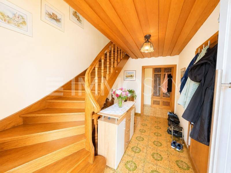 Eingangsbereich mit Holztreppe, Garderobe und traditionellem Bodenbelag.