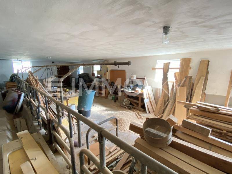 Großer Werkstattraum mit Holzbrettern und Arbeitsmaterialien, ideal für handwerkliche Tätigkeiten.