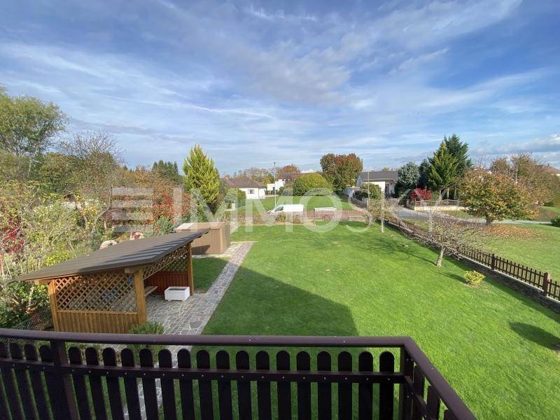 Großer, gepflegter Garten mit weitläufiger Rasenfläche, einem Holzpavillon und umgebendem Zaun.