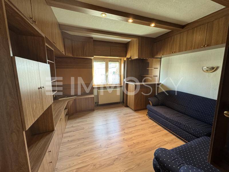 Gemütliches Wohnzimmer mit Holzvertäfelung, Einbauschränken und Sofa.