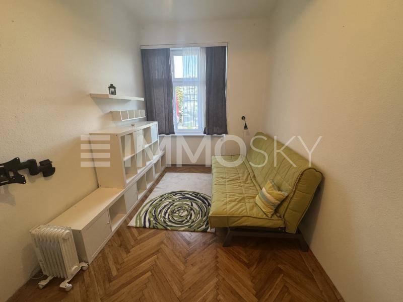 Heller Wohnbereich mit Fenster, grünem Sofa und praktischen Regalen.