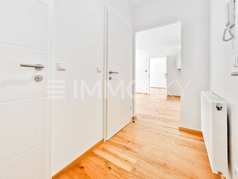 Heller Flur mit Holzboden und weißen Türen, der zu weiteren Räumen der Wohnung führt.