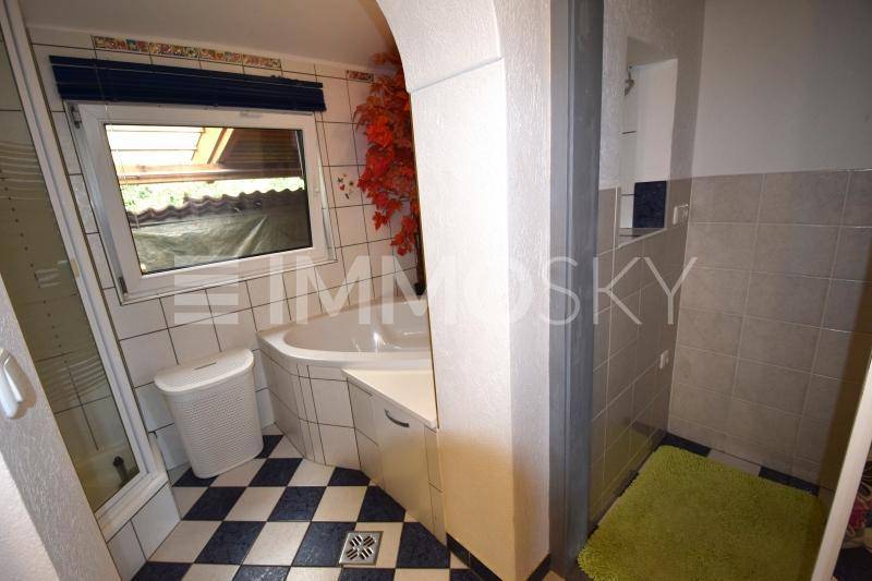 Badezimmer mit Eckbadewanne, separater Dusche und einem Fenster, ausgestattet mit schwarz-weißem Fliesenboden.